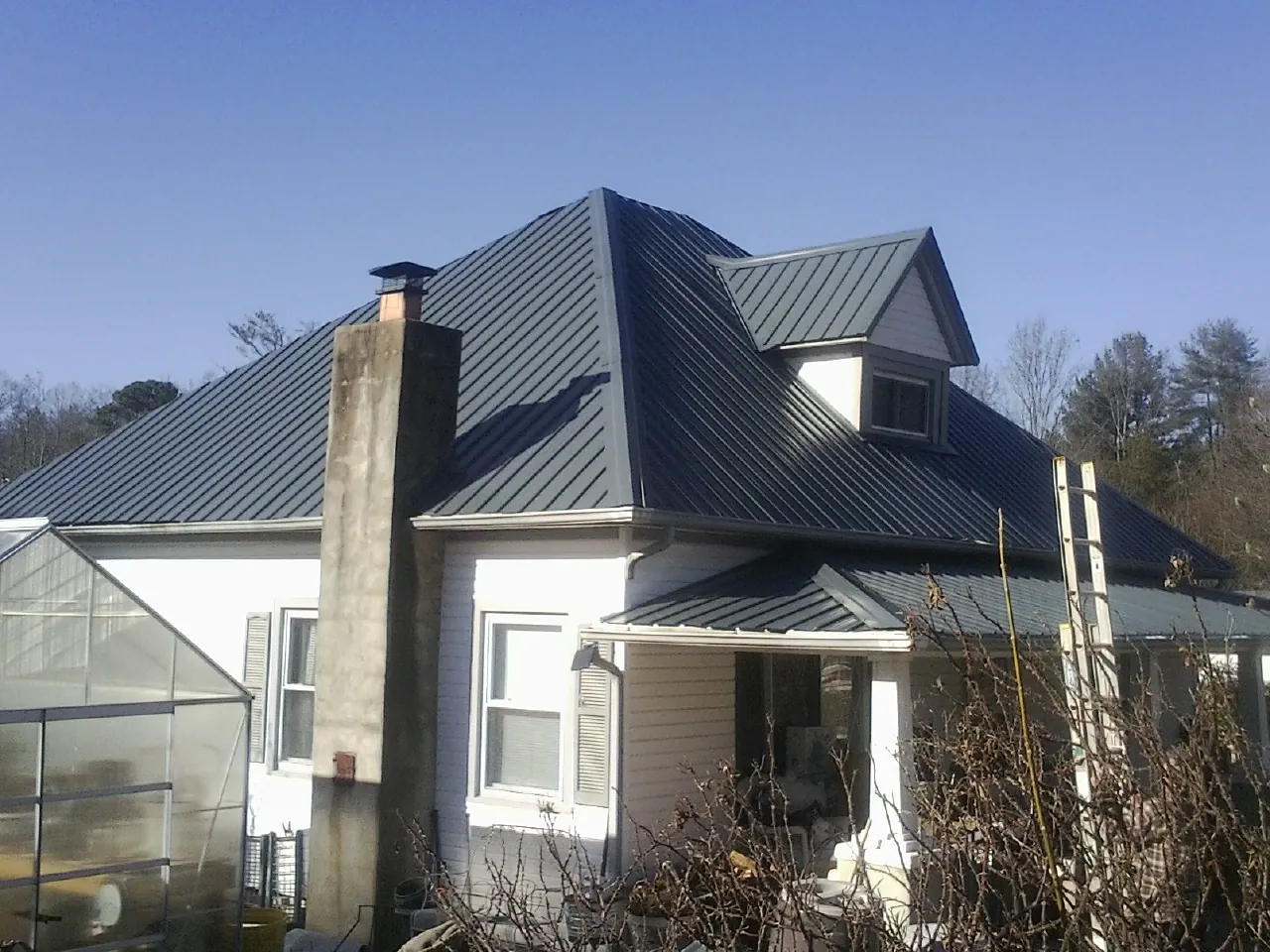 Dark blue standing seam metal roof on a white farmhouse with dormer — Slate & Tile Roof Repair by Roofing Brothers in Thousand Palms