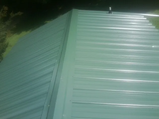 New green metal panels meeting at the ridge of a roof — Flat Roof Repair work by our crew in Thousand Palms