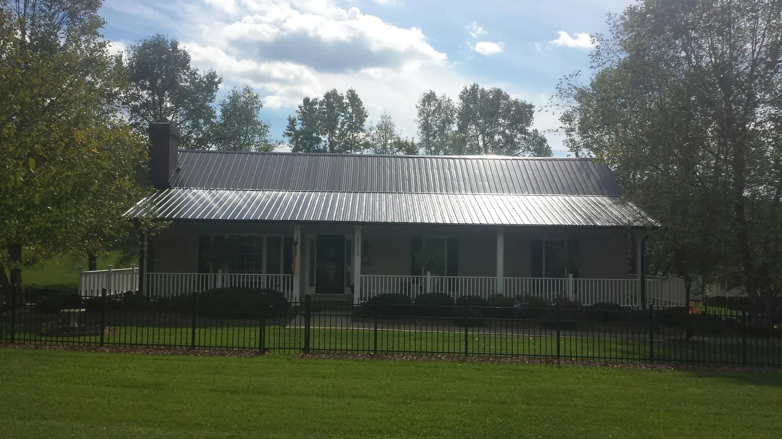 Gray metal roof on a brick ranch with a full width front porch — Gutter Guard Installation work by our crew in Thousand Palms