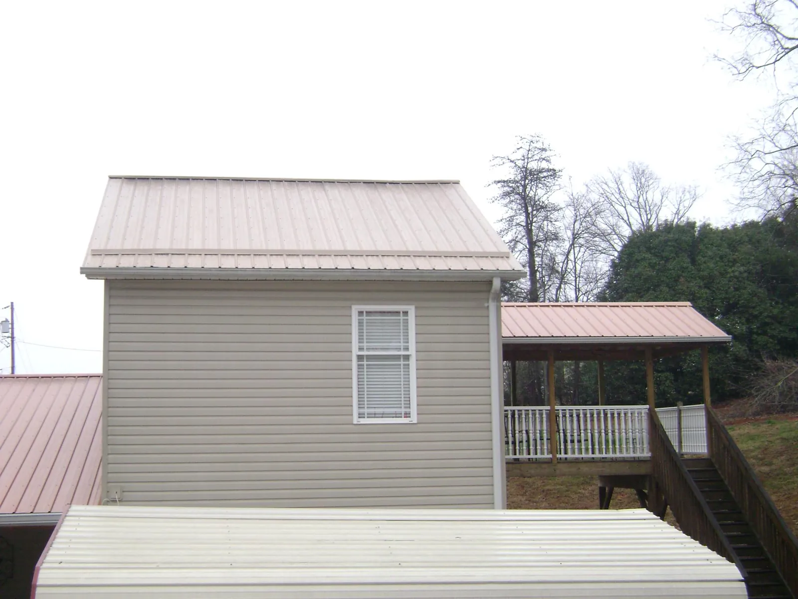 Tan metal roofs on a two story addition and attached porch, from a Roof Replacement job in Thousand Palms