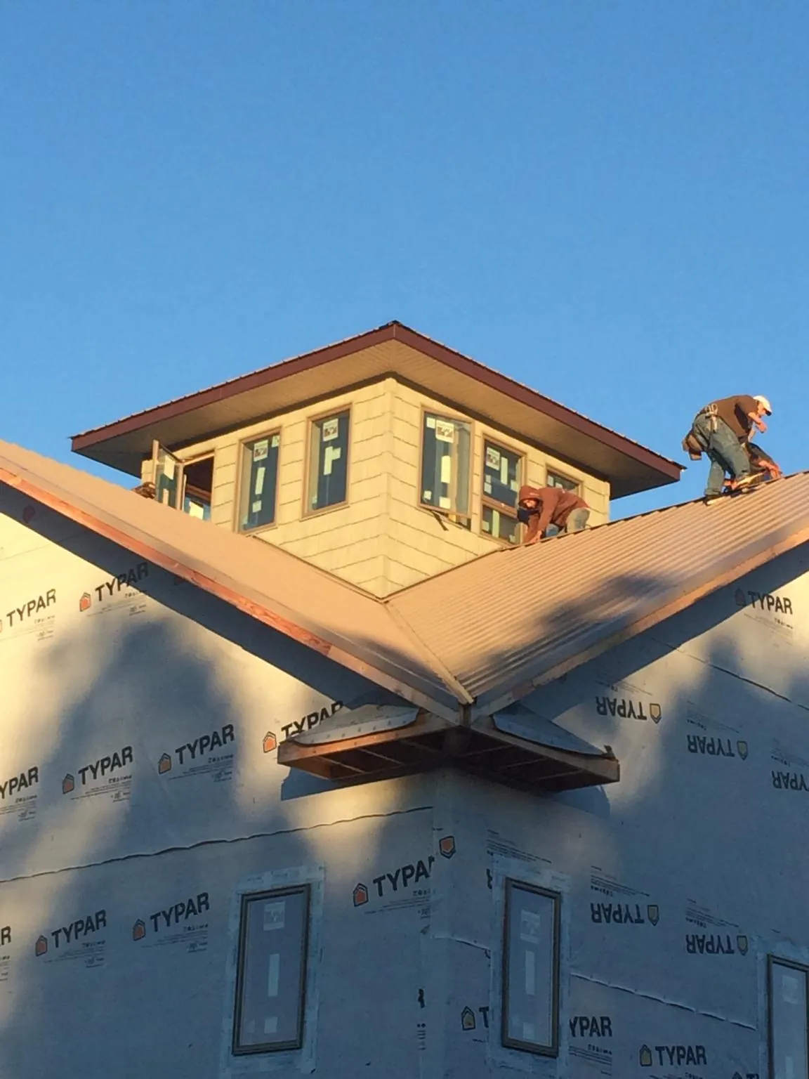 Roofers working around a rooftop cupola on a new metal roof at sunset — Roof Waterproofing in Thousand Palms by Roofing Brothers